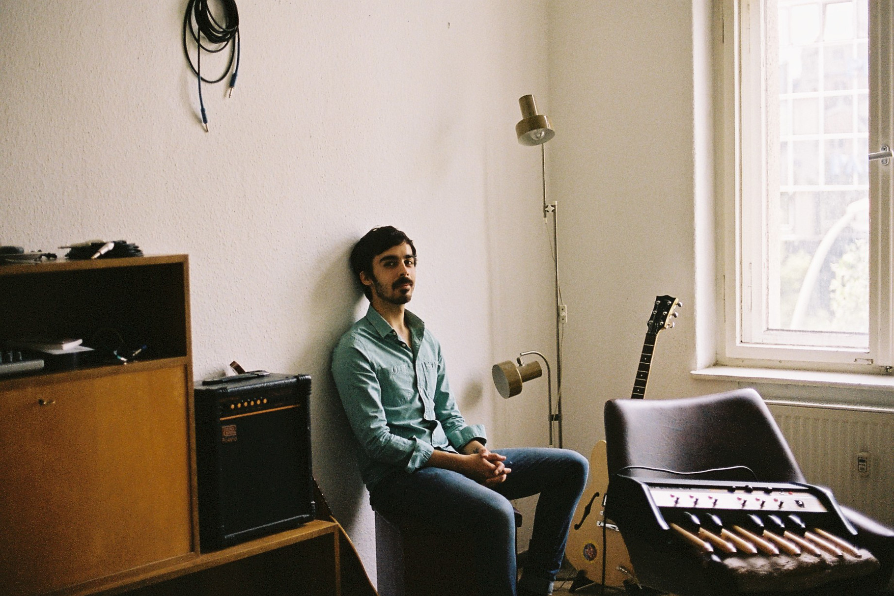 Will Samson by Sebastian Urzendowsky, artist sat in white room surrounded by musical instruments and equipment