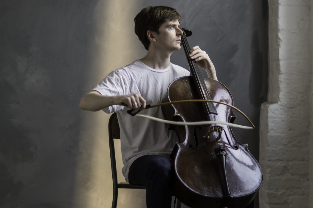 Oliver Coates, cellist sat in church or temple-like stone building