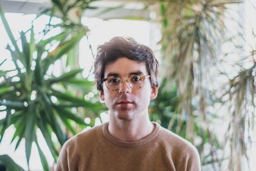 Matt Carlson - The View From Nowhere, artist stood in front of large houseplants