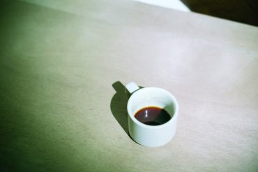 Marc Baron - Un salon au fond d'un lac, a white cup of coffee sat on a wooden table