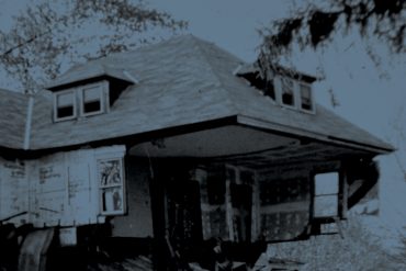 Olivia Block - Dissolution, blue-tinted photograph of a ruined house with some external walls missing, giving a view of a wallpapered room