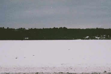 Clara de Asís + Bruno Duplant - L'inertie, dark shore seen from the middle of a frozen snow-covered lake, cobalt sky