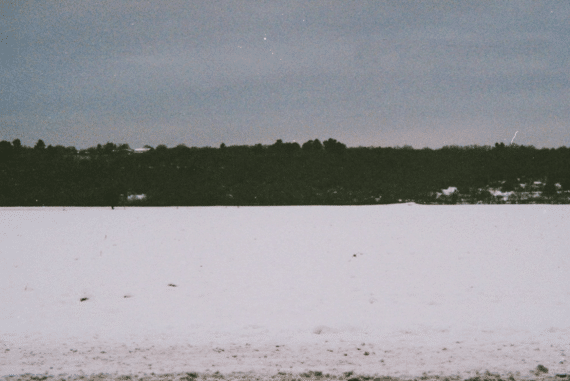 Clara de Asís + Bruno Duplant - L'inertie, dark shore seen from the middle of a frozen snow-covered lake, cobalt sky