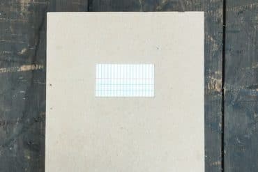 Ryoko Akama - places and pages, a large grey notebook on a dark wooden surface