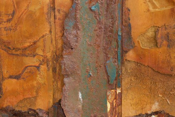 Jake Muir - Acclimation, closeup of rusted orange and blue industrial surfaces that resemble sheets of rock