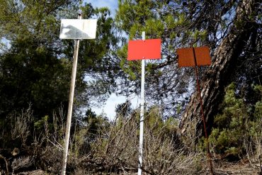 Kate Carr - From A Wind Turbine To Vultures (and back), three metal signs on a hillside.