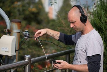 Simon Whetham - Open and Closed Circles, artist outdoors recording sounds from electrical wires.