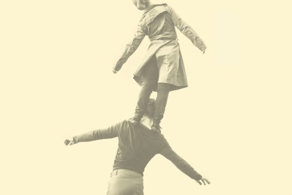 Machinefabriek - Engel, female dancer stood on male dancer's shoulders against a pale yellow background