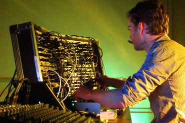 Thomas Ankersmit - Homage to Dick Raaijmakers, artist performing with Serge Modular Synth against a yellow background.